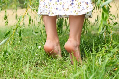 Photo of Woman walking barefoot on green grass outdoors, closeup