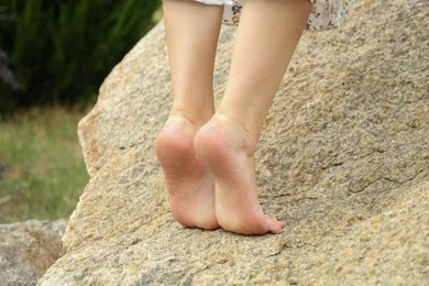 Photo of Woman standing barefoot on rock outdoors, closeup