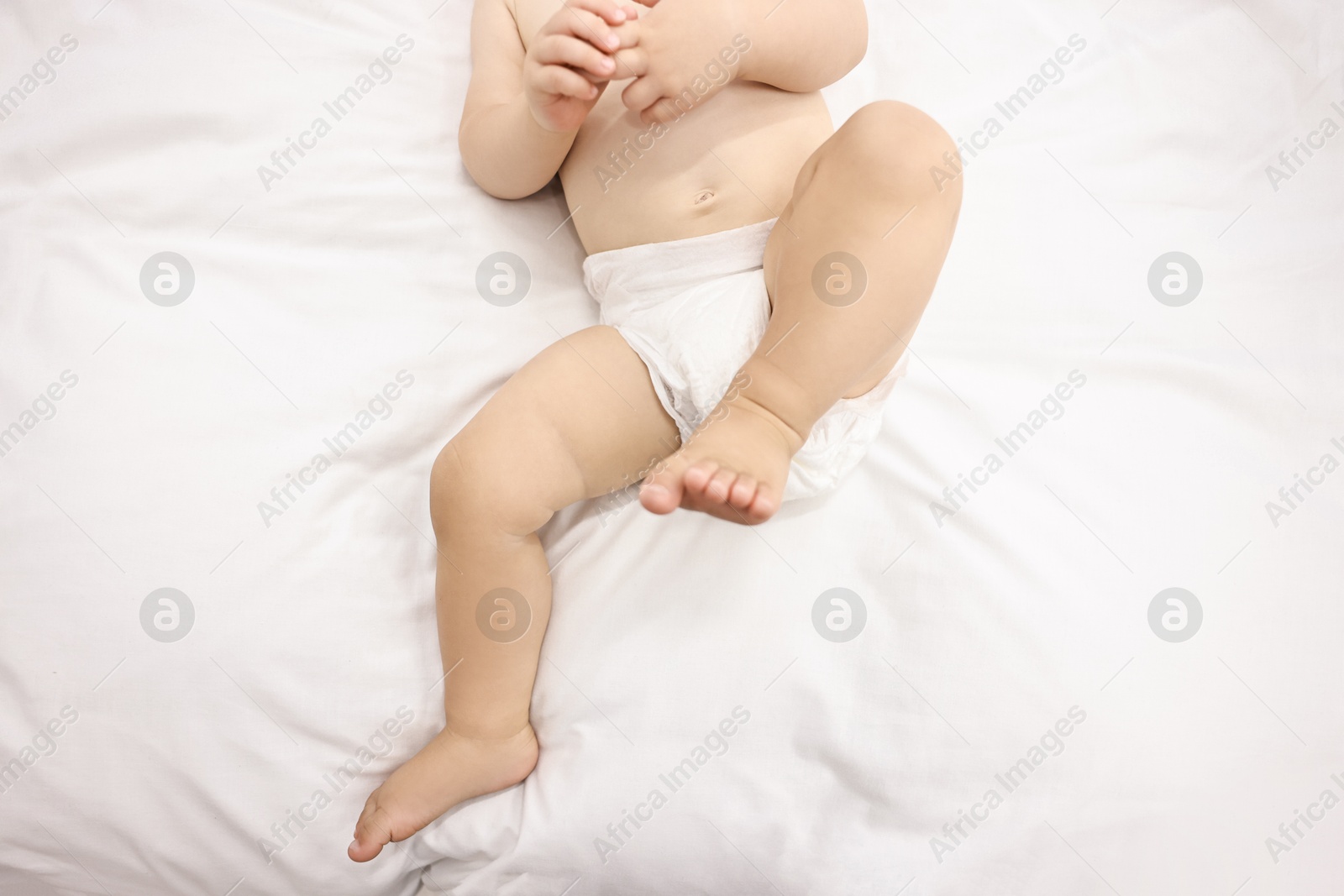 Photo of Little child in diaper on bed, closeup