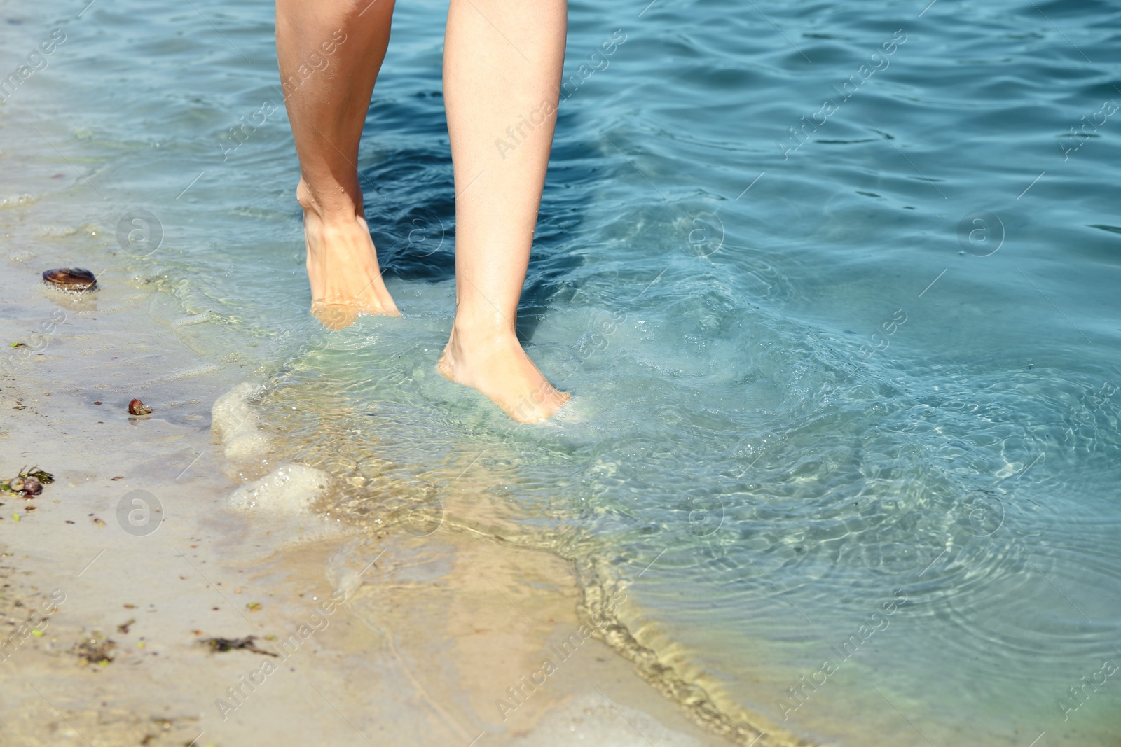 Photo of Woman walking barefoot through water on riverbank, closeup