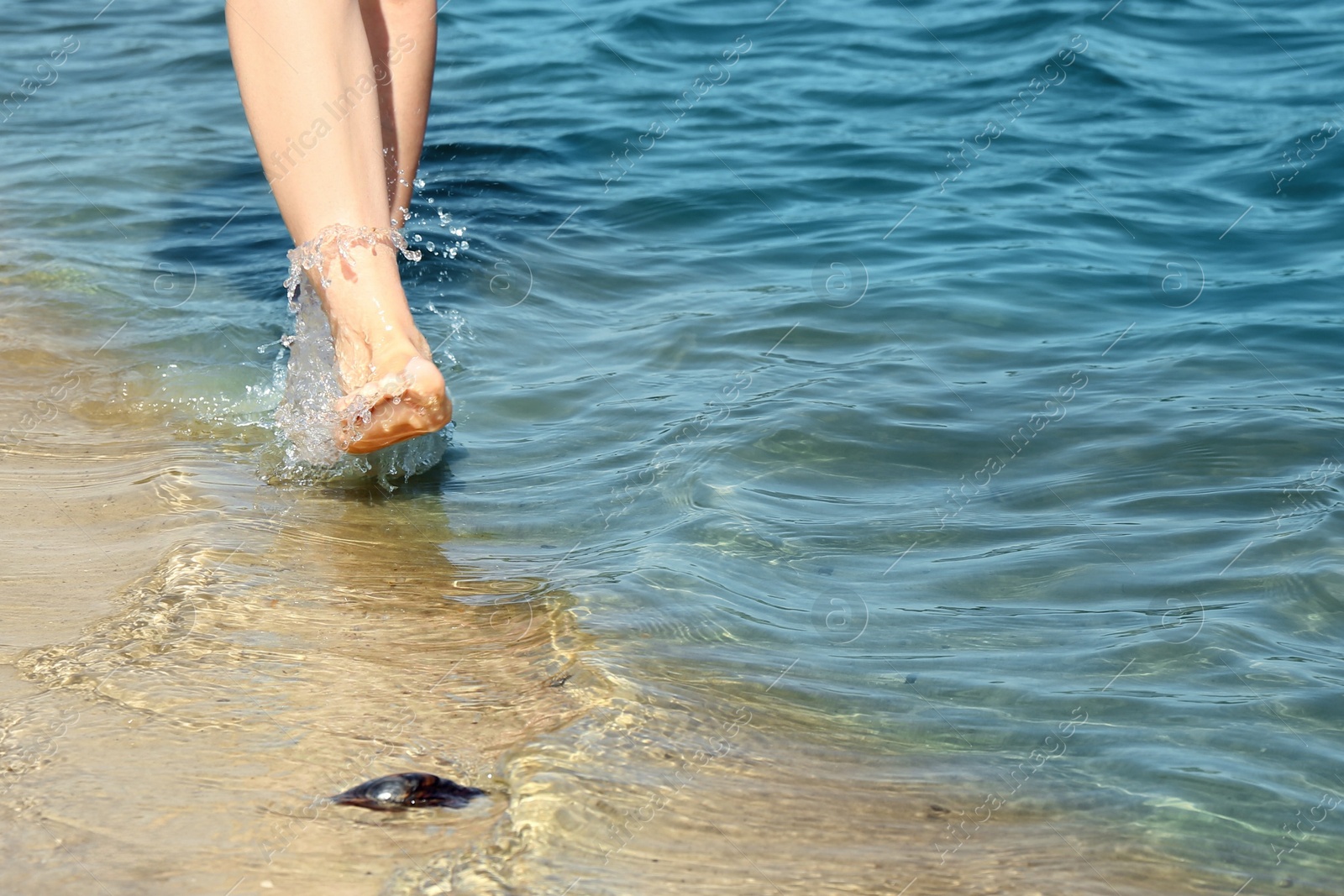 Photo of Woman walking barefoot through water on riverbank, closeup