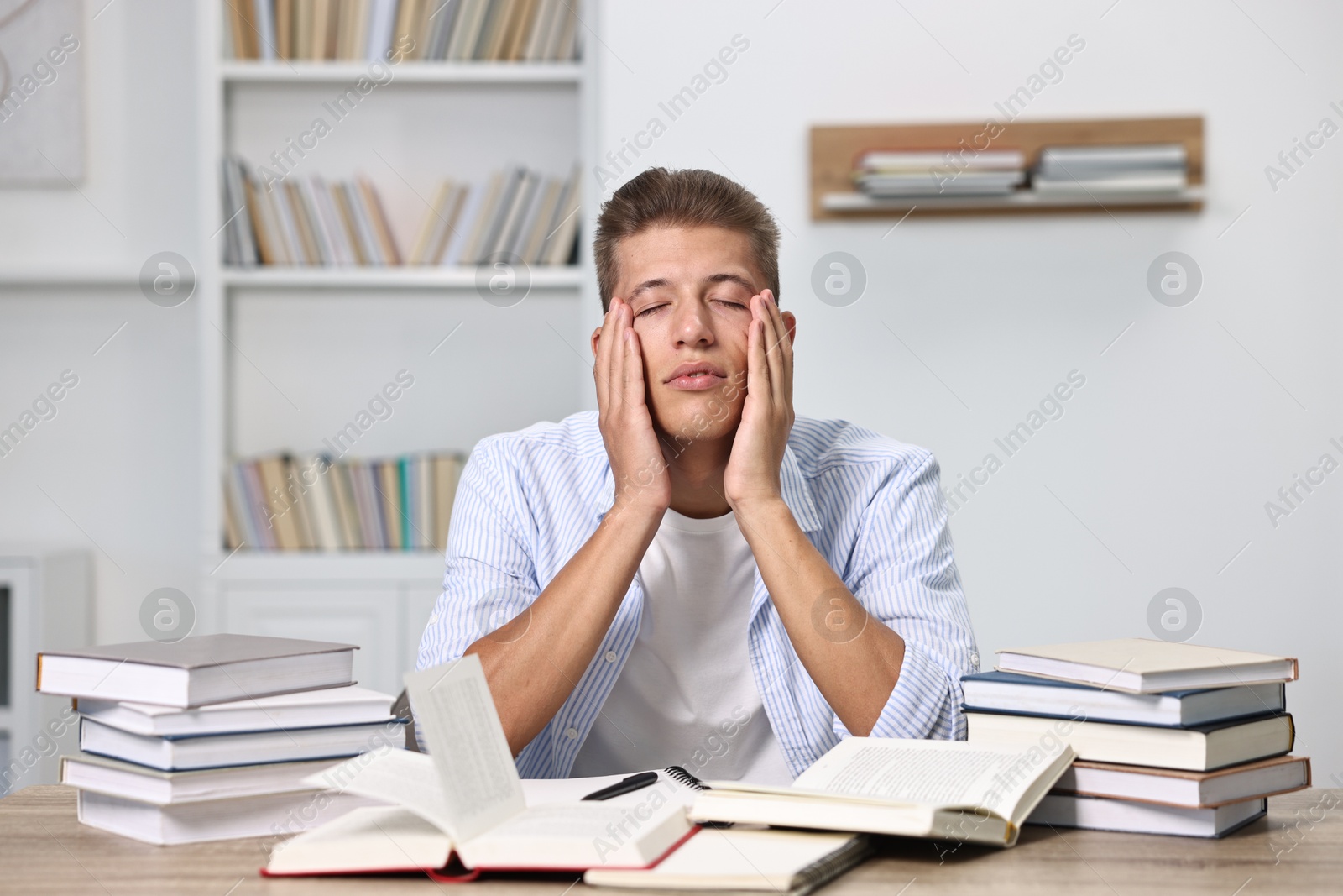 Photo of Overwhelmed student before exam at table among books indoors