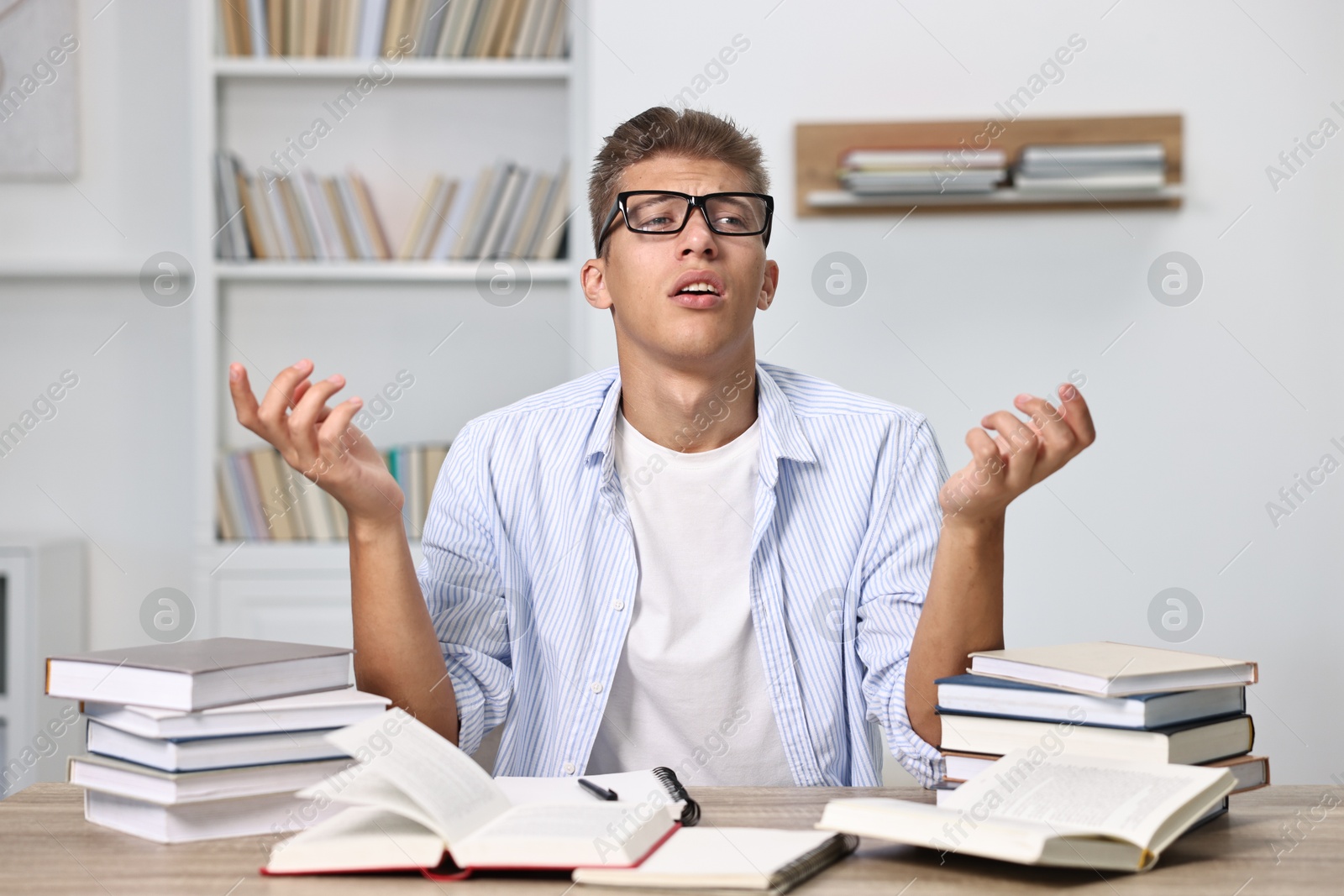 Photo of Tired student before exam at table among books indoors