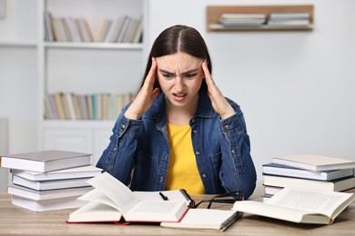 Photo of Excited student before exam at table among books indoors