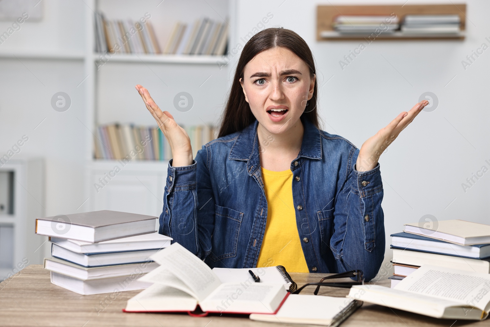 Photo of Excited student before exam at table among books indoors