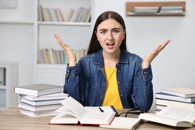 Excited student before exam at table among books indoors