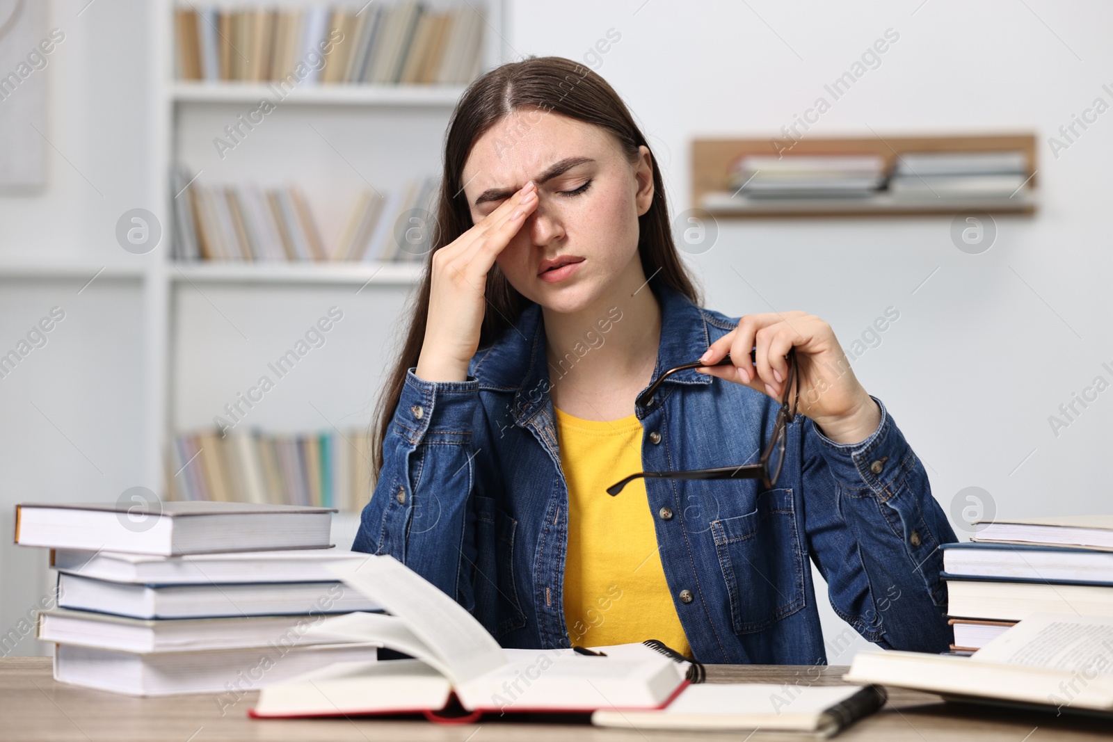 Photo of Tired student before exam at table among books indoors