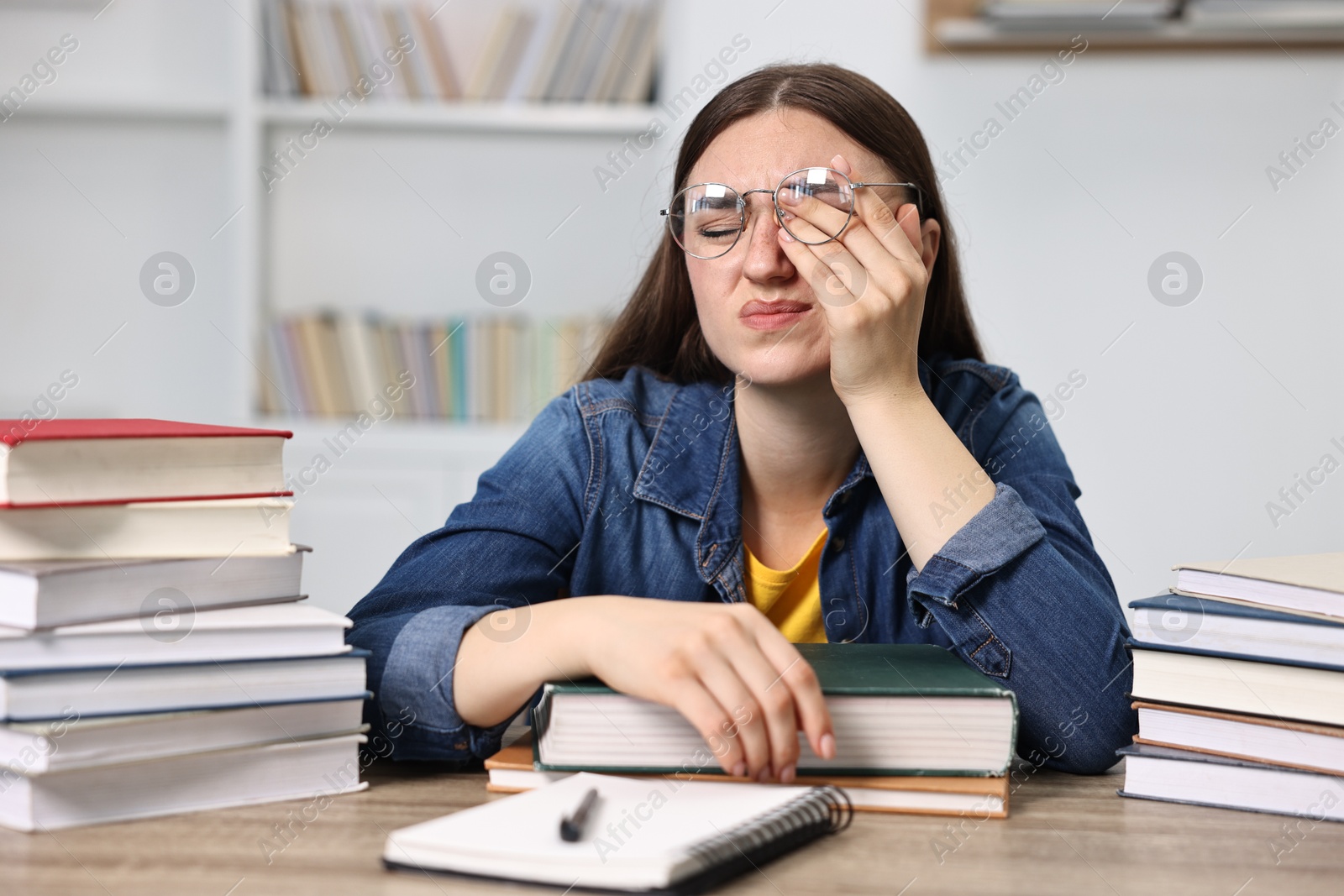 Photo of Overwhelmed student before exam at table among books indoors