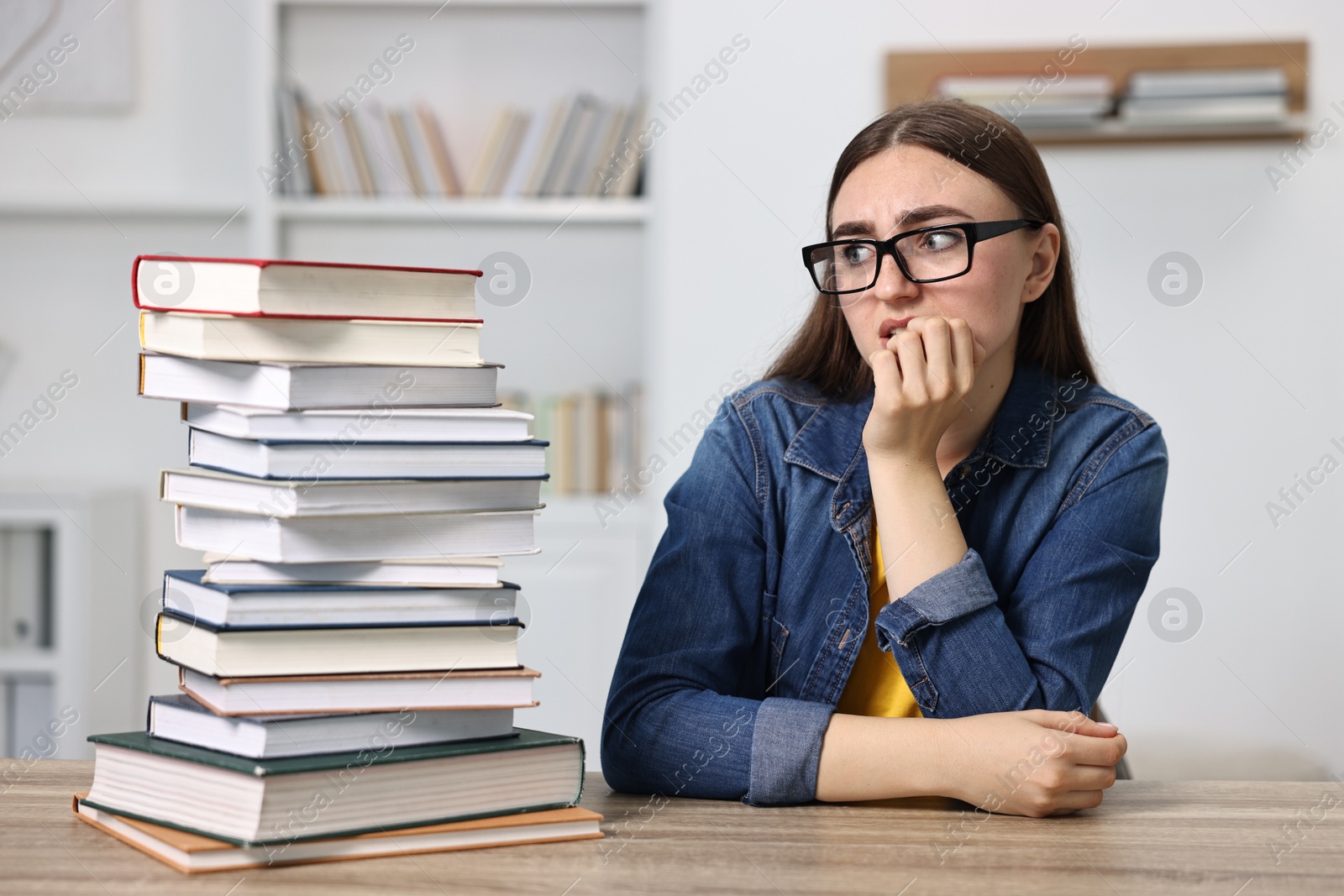 Photo of Overwhelmed student before exam at table among books indoors