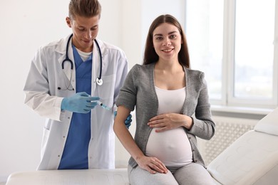 Photo of Doctor giving injection to pregnant woman at hospital