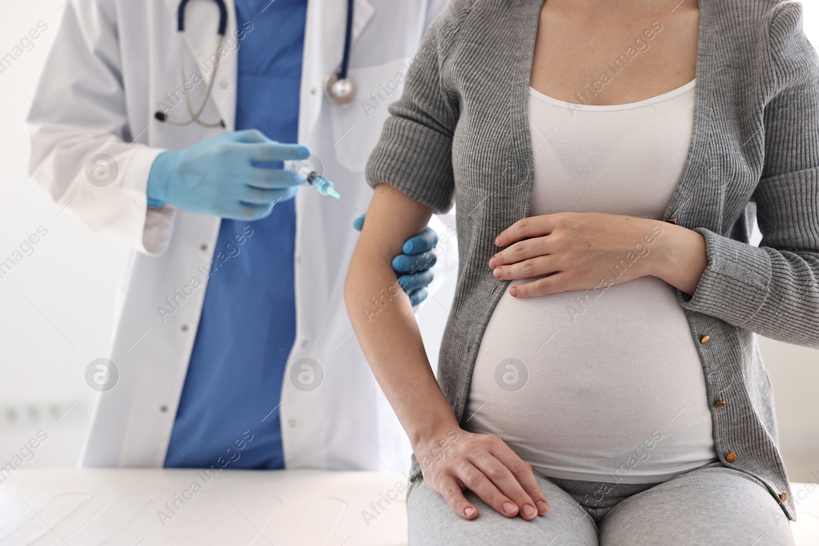 Photo of Doctor giving injection to pregnant woman at hospital, closeup