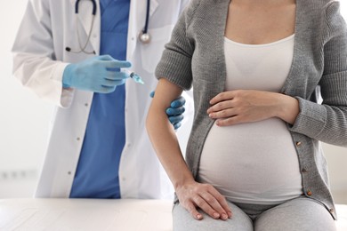 Photo of Doctor giving injection to pregnant woman at hospital, closeup