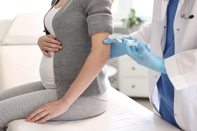 Photo of Doctor giving injection to pregnant woman at hospital, closeup