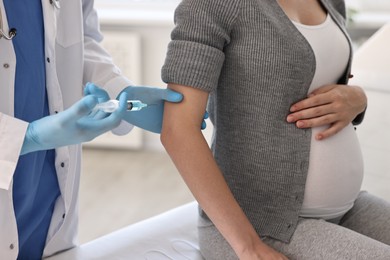 Photo of Doctor giving injection to pregnant woman at hospital, closeup