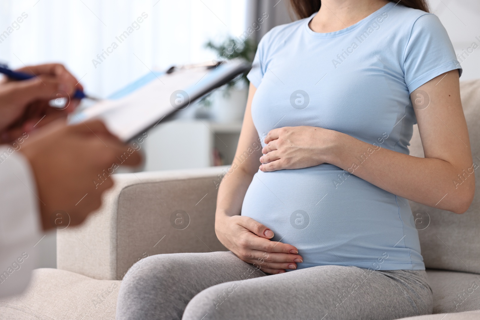 Photo of Doctor with clipboard consulting pregnant patient indoors, closeup