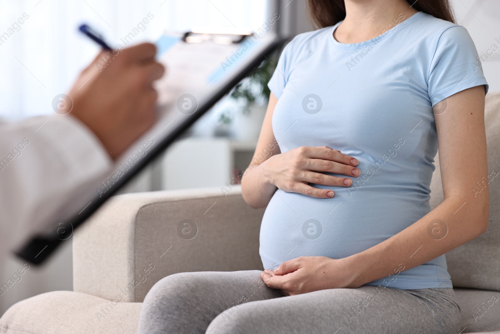 Photo of Doctor with clipboard consulting pregnant patient indoors, closeup