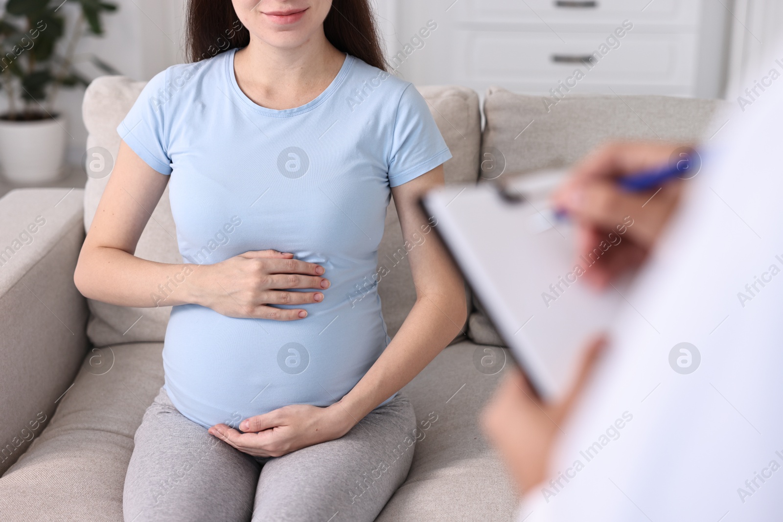 Photo of Doctor with clipboard consulting pregnant patient indoors, closeup