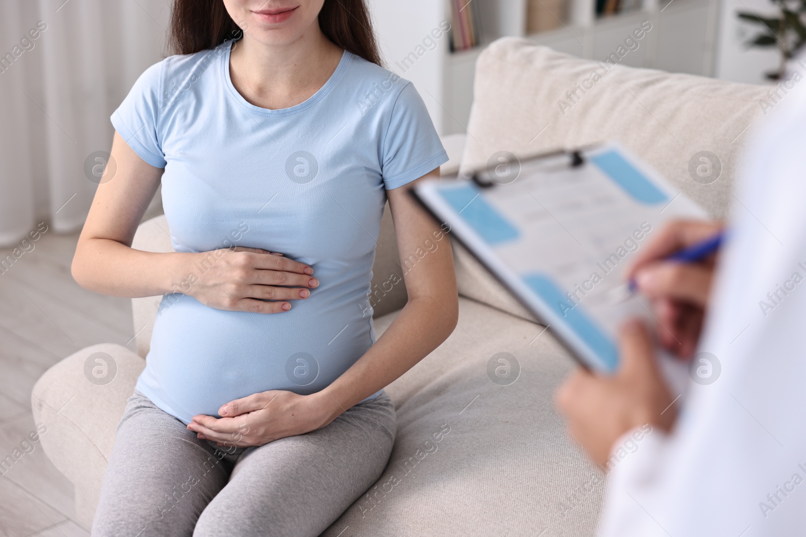 Photo of Doctor with clipboard consulting pregnant patient indoors, closeup