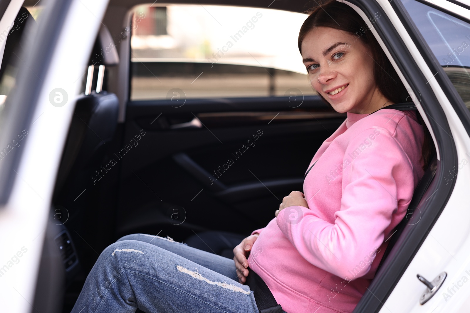 Photo of Smiling pregnant woman with safety belt in car