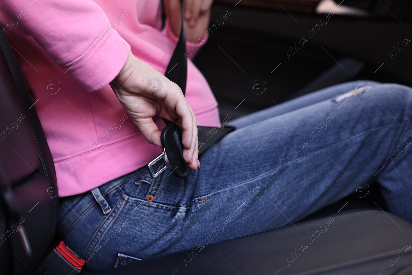 Photo of Pregnant woman fastening safety belt in car, closeup