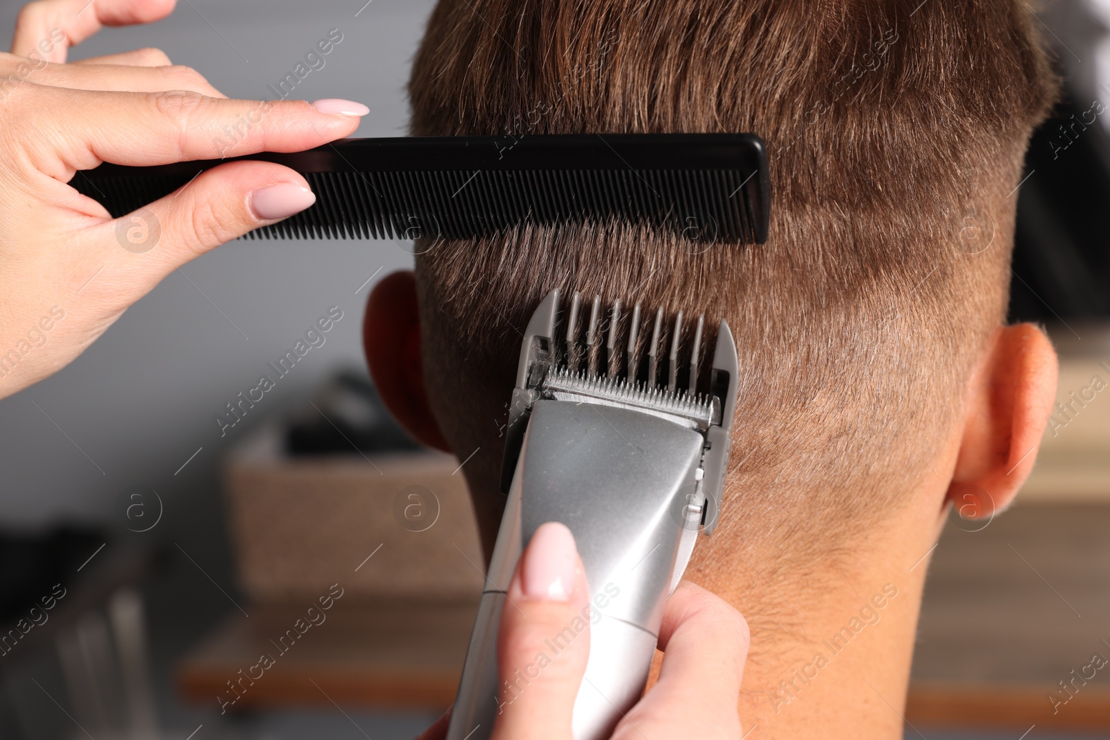 Photo of Professional barber making stylish haircut in salon, closeup