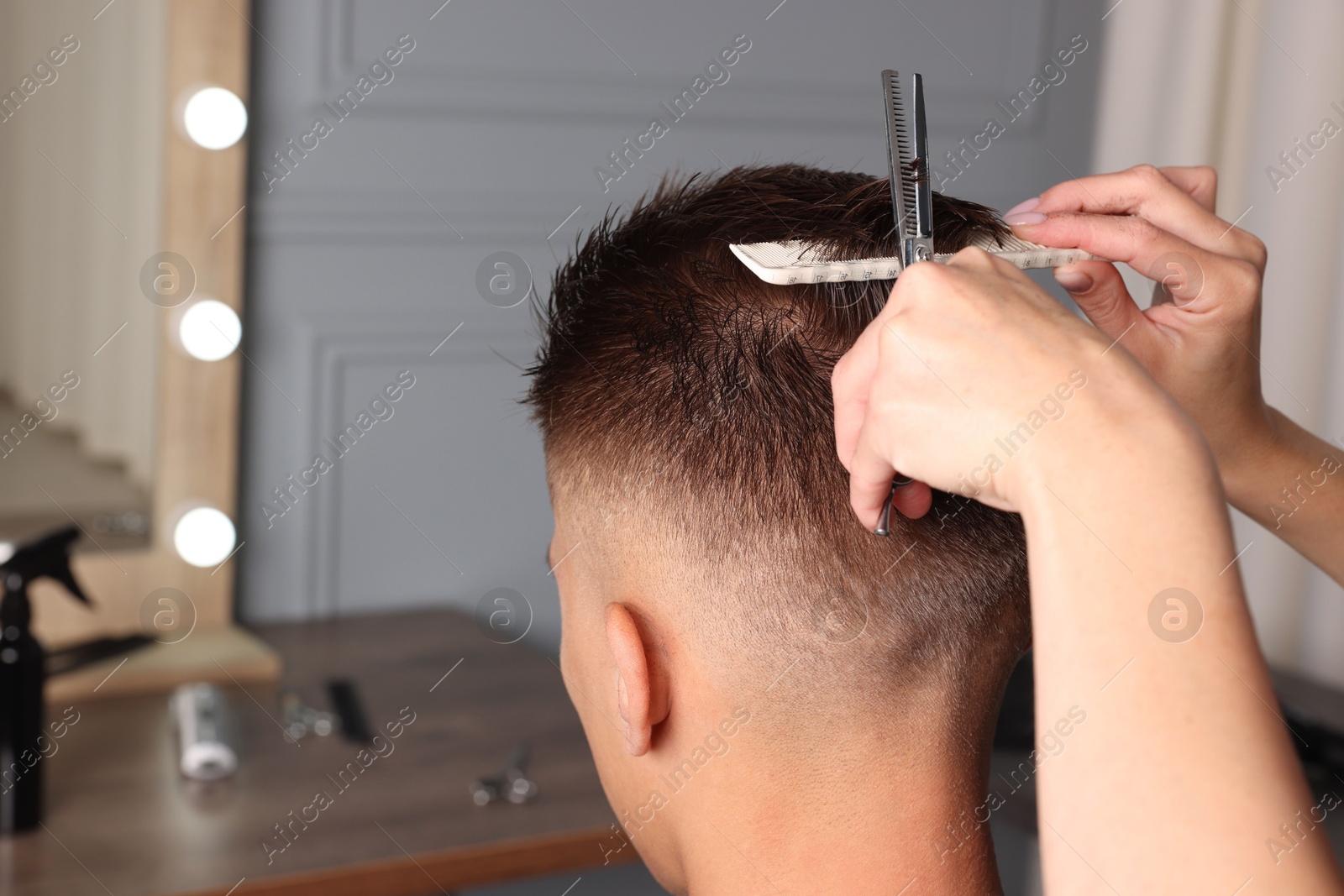 Photo of Professional hairdresser cutting client's hair with scissors in barbershop, closeup