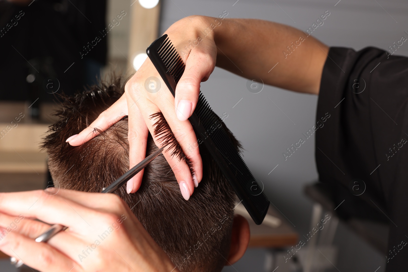 Photo of Professional hairdresser cutting client's hair with scissors in barbershop, closeup