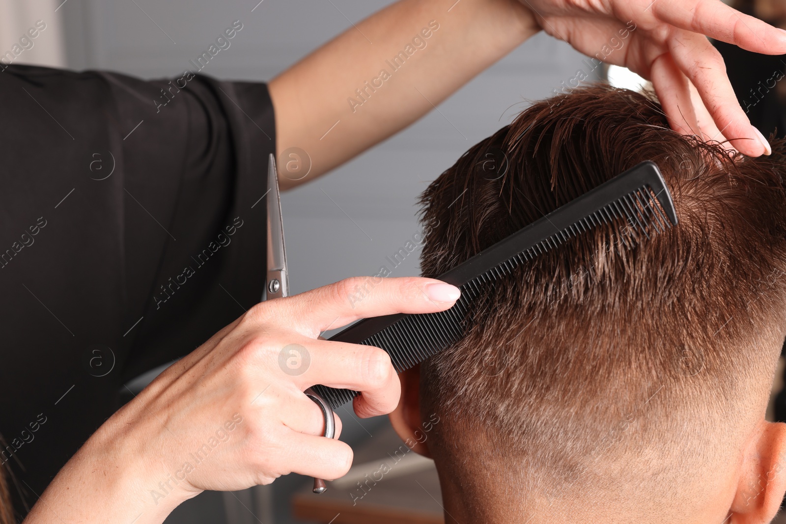 Photo of Hair cutting. Hairdresser combing man's hair in barbershop, closeup