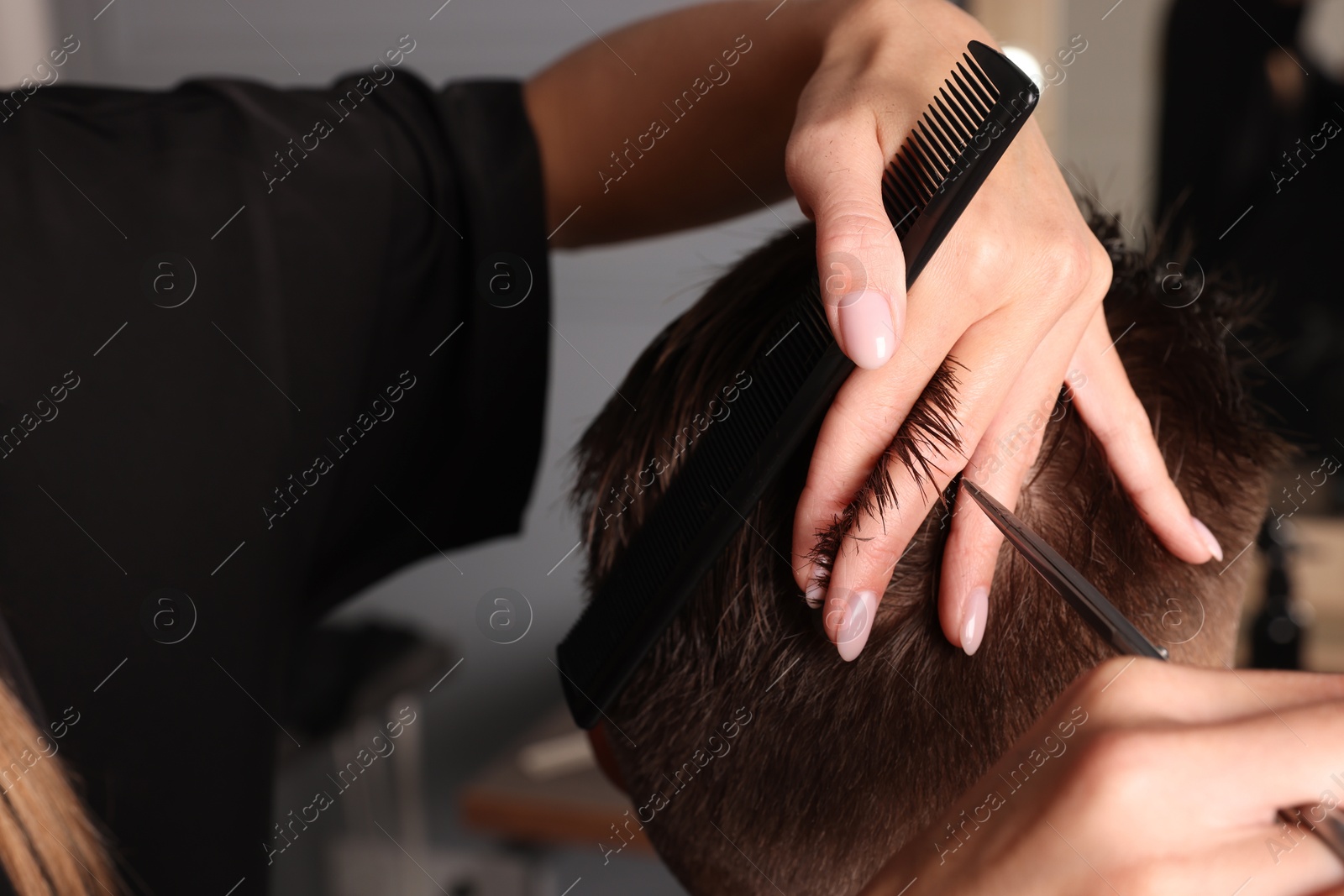 Photo of Professional hairdresser cutting client's hair with scissors in barbershop, closeup