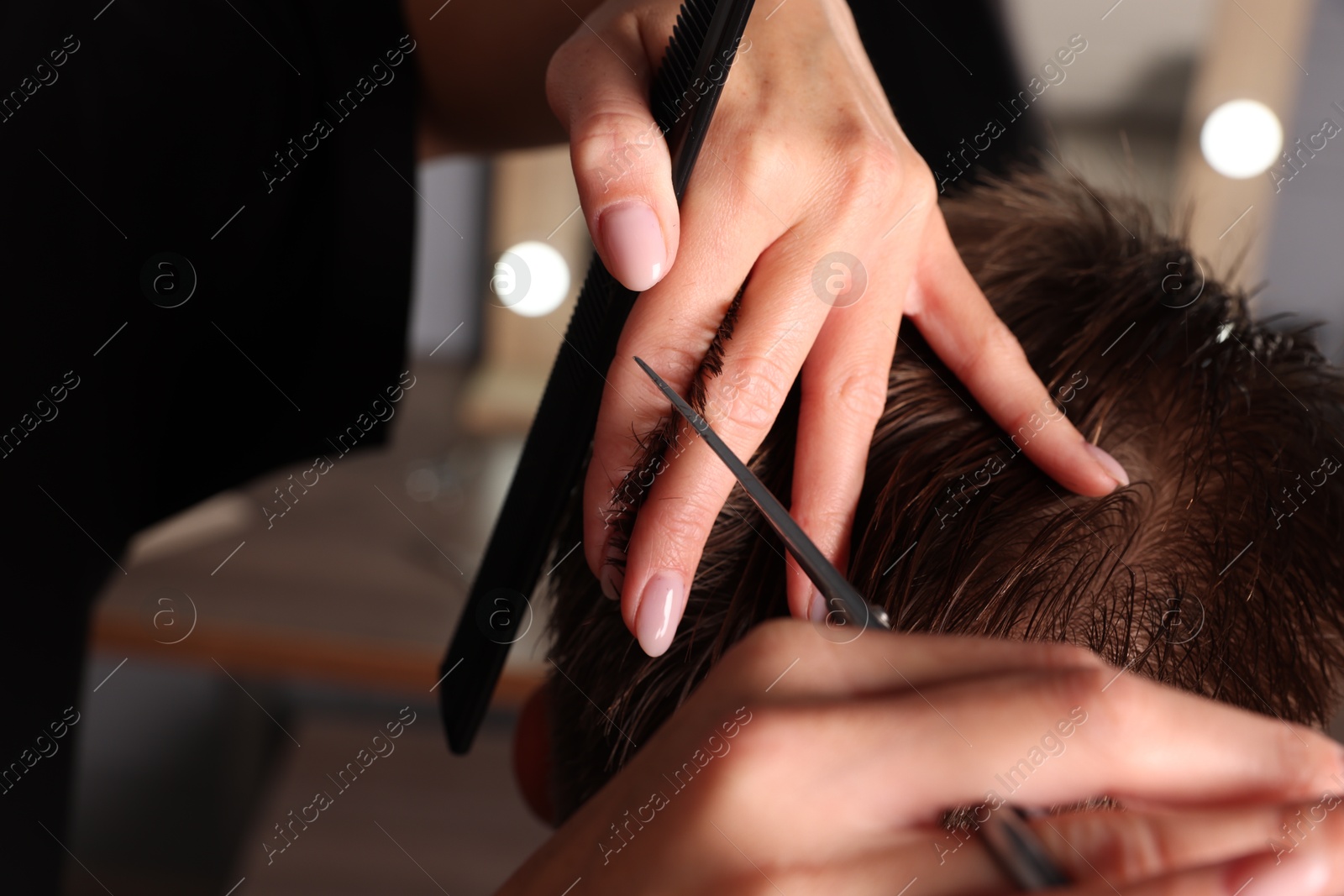 Photo of Professional hairdresser cutting client's hair with scissors in barbershop, closeup