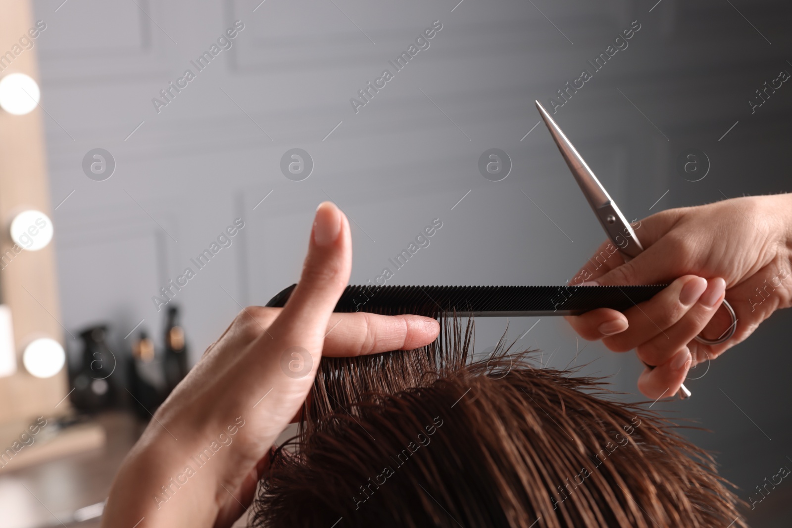 Photo of Professional hairdresser cutting client's hair with scissors in barbershop, closeup