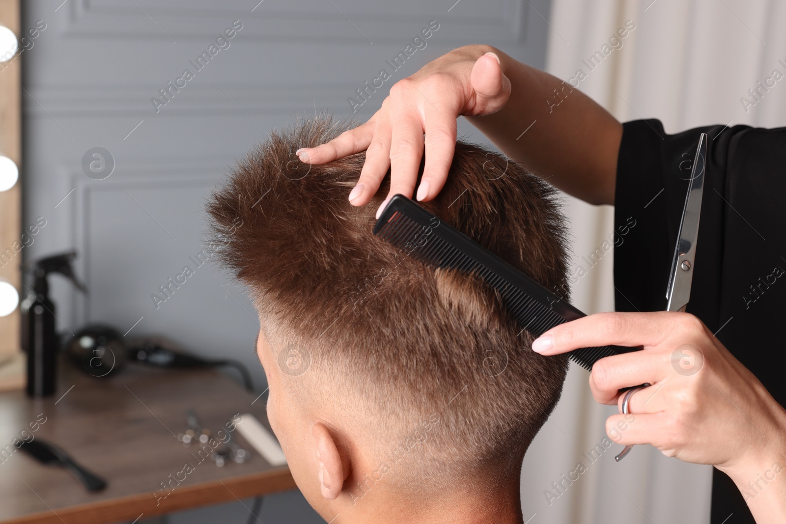 Photo of Professional barber making stylish haircut in salon, closeup