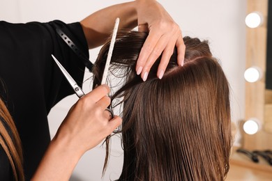 Hair cutting. Professional hairdresser working with client in salon, closeup