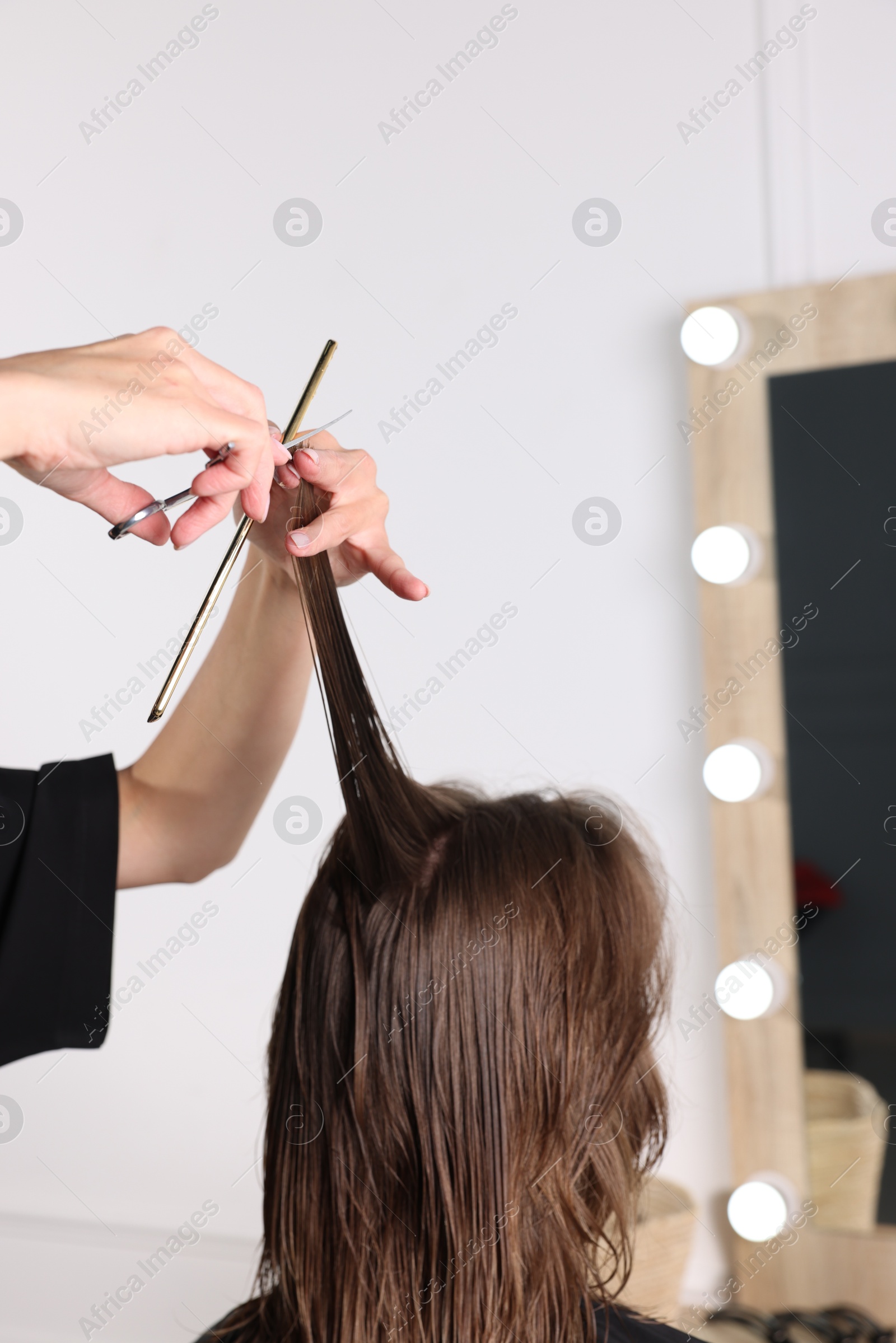 Photo of Hairdresser cutting client's hair with scissors in salon, closeup