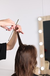 Photo of Hairdresser cutting client's hair with scissors in salon, closeup