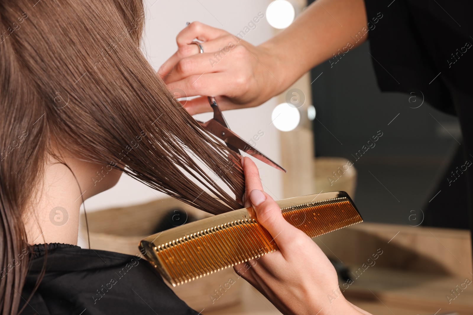 Photo of Hairdresser cutting client's hair with scissors in salon, closeup