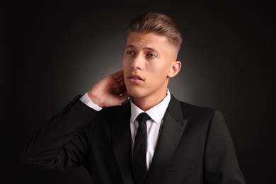 Confident young man with stylish haircut on black background