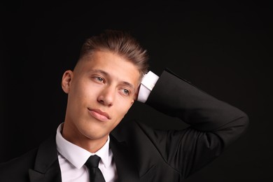 Confident young man with stylish haircut on black background