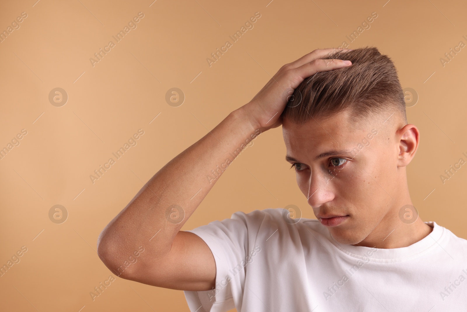 Photo of Confident young man with stylish haircut on light brown background. Space for text