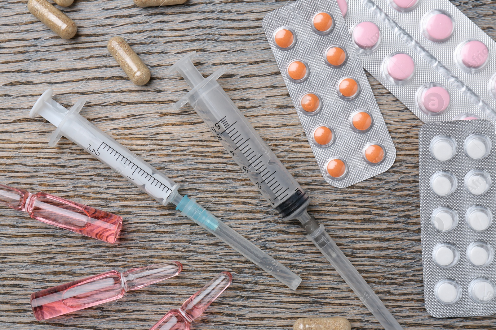 Photo of Pharmacist. Many different pills, syringes and ampoules on wooden table, flat lay