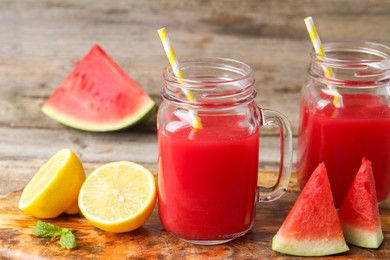 Photo of Tasty watermelon drink in mason jars and fresh fruits on wooden table, closeup