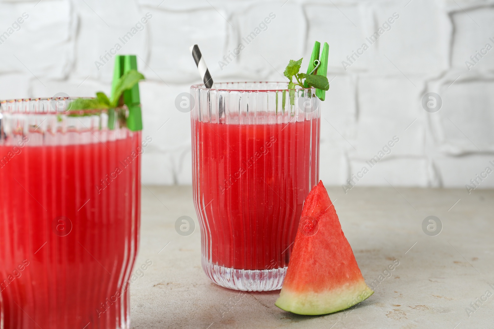 Photo of Delicious watermelon drink in glasses, fresh fruits and mint on light table, closeup