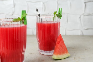 Photo of Delicious watermelon drink in glasses, fresh fruits and mint on light table, closeup