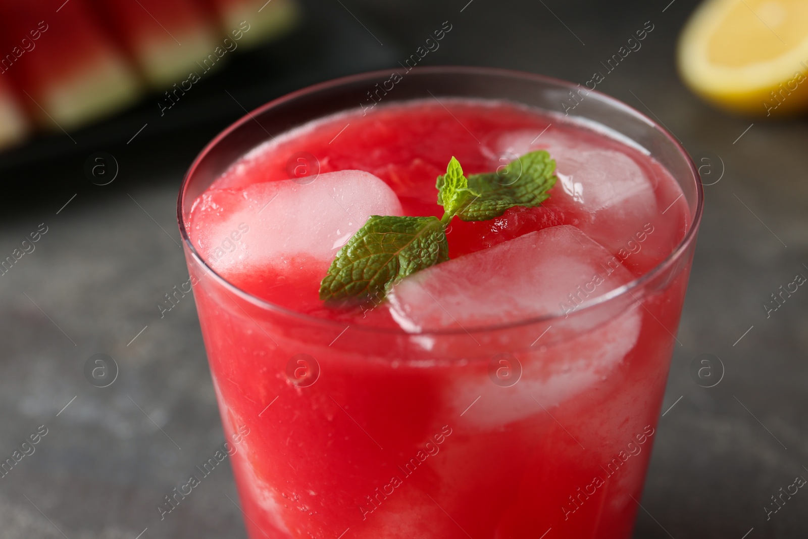 Photo of Tasty watermelon drink in glass and mint on blurred background, closeup