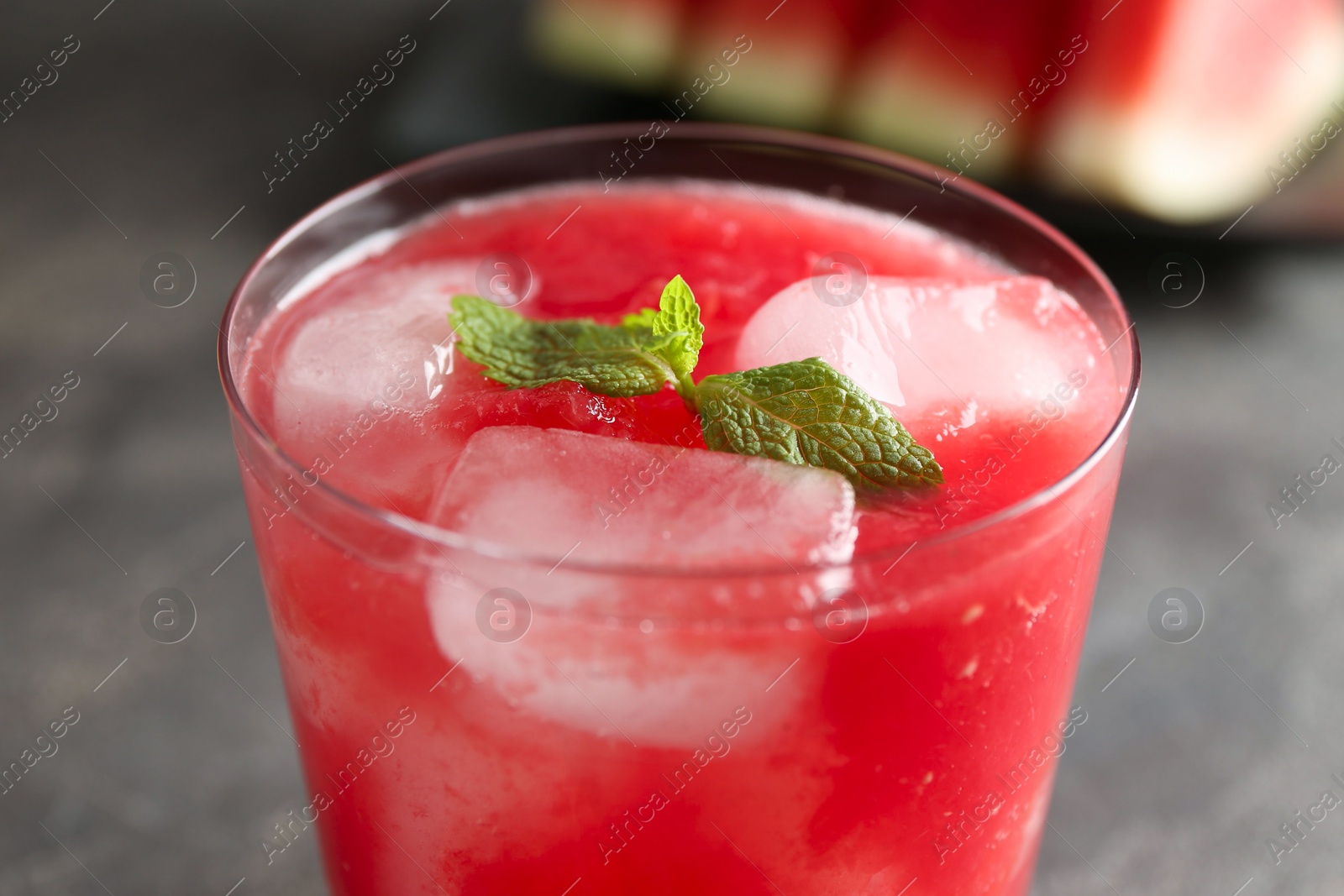 Photo of Tasty watermelon drink in glass and mint on blurred background, closeup