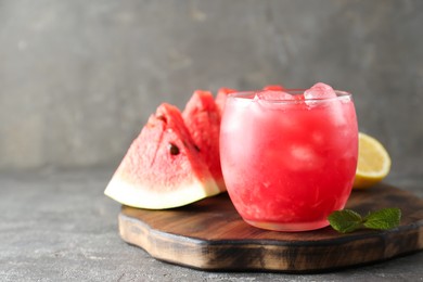 Photo of Tasty watermelon drink in glass, fresh fruits and mint on grey table, closeup