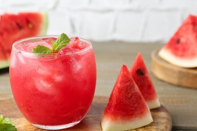 Photo of Tasty watermelon drink in glass, mint and fresh fruit on wooden table, closeup