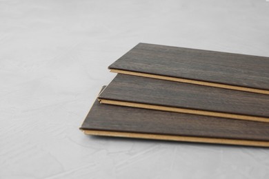 Photo of Laminate flooring pieces on grey textured surface, closeup