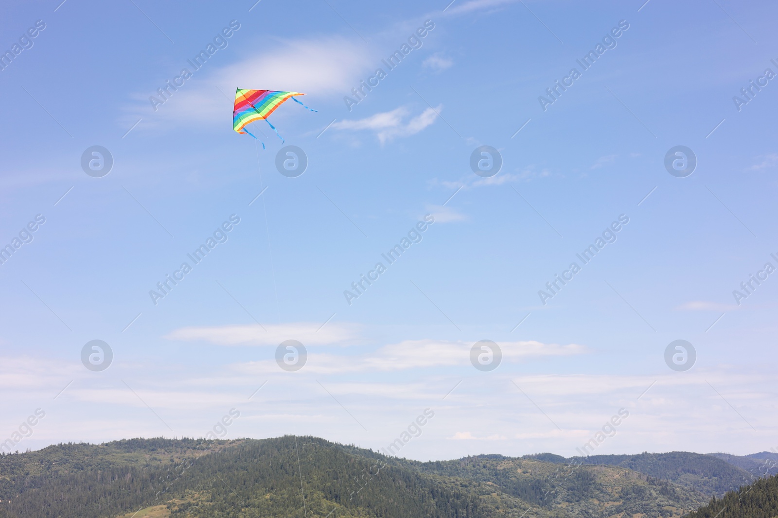 Photo of One colorful kite flying in mountains under blue sky