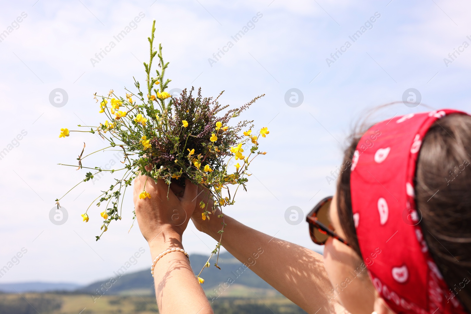 Photo of Woman holding bouquet of wild yellow flowers outdoors